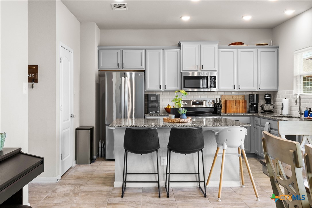 7468 Mossy Ridge Lane Temple, TX 76502 - Photo 10 of 38 a kitchen with stainless steel appliances granite countertop a stove a sink a refrigerator and white cabinets