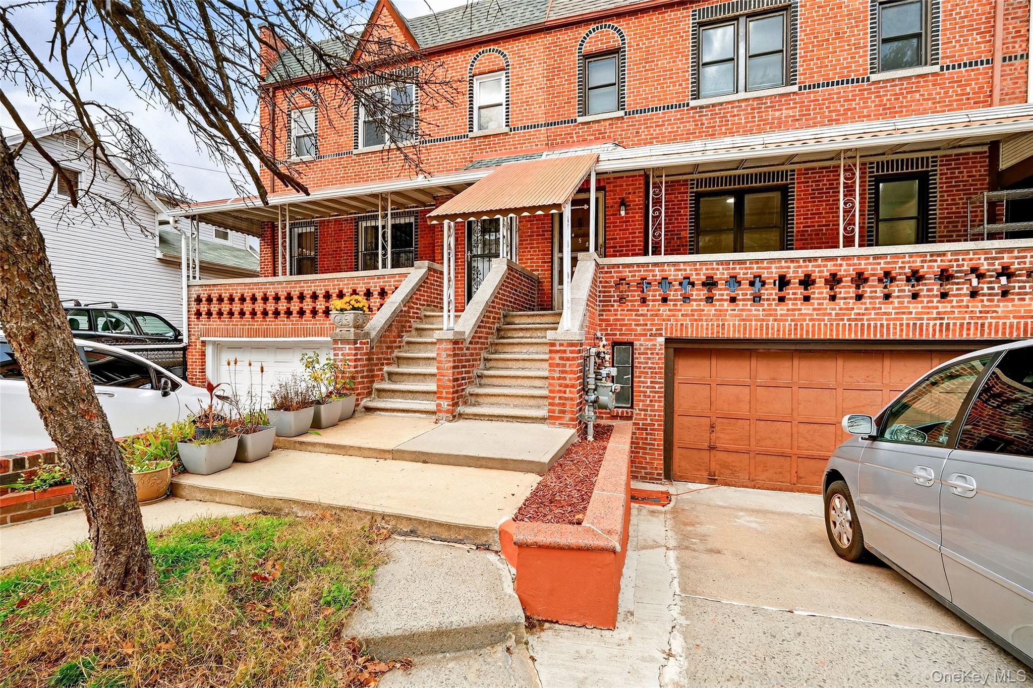 1458 Rowland Street Bronx, NY 10461 - Photo 13 of 49 View of front of house featuring brick siding, driveway, covered porch, and a garage