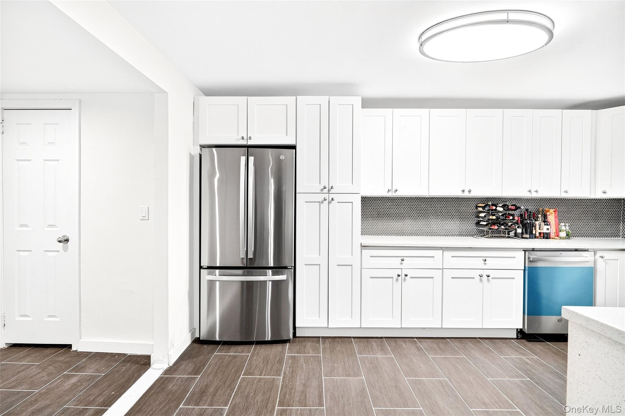 1458 Rowland Street Bronx, NY 10461 - Photo 26 of 49 Kitchen with appliances with stainless steel finishes, white cabinetry, wood tiled floors, light stone countertops, and backsplash