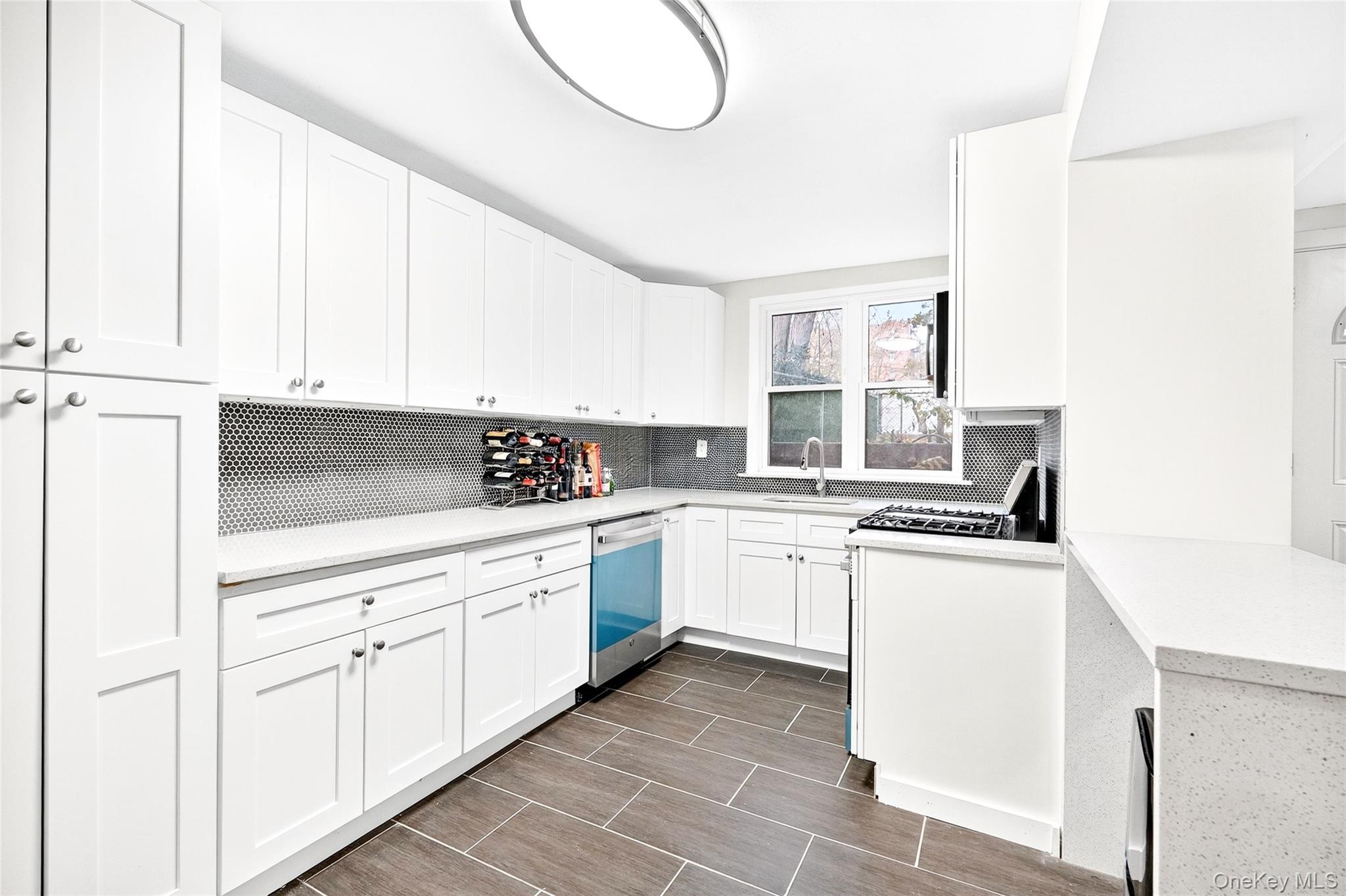 1458 Rowland Street Bronx, NY 10461 - Photo 27 of 49 Kitchen with white cabinetry, decorative backsplash, stainless steel appliances, light stone counters, and wood finish floors