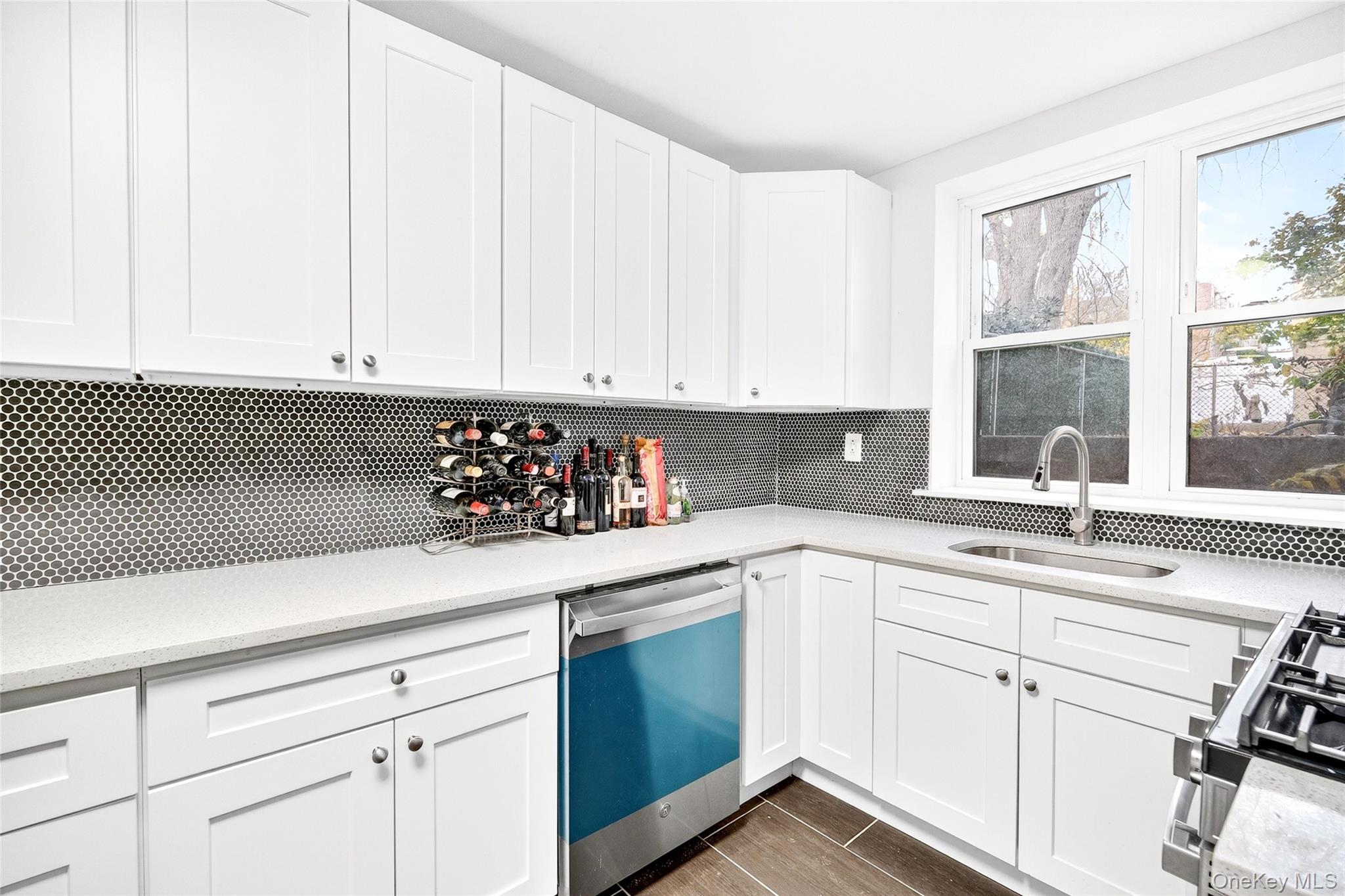 1458 Rowland Street Bronx, NY 10461 - Photo 28 of 49 Kitchen with stainless steel dishwasher, white cabinetry, gas range, and light stone countertops