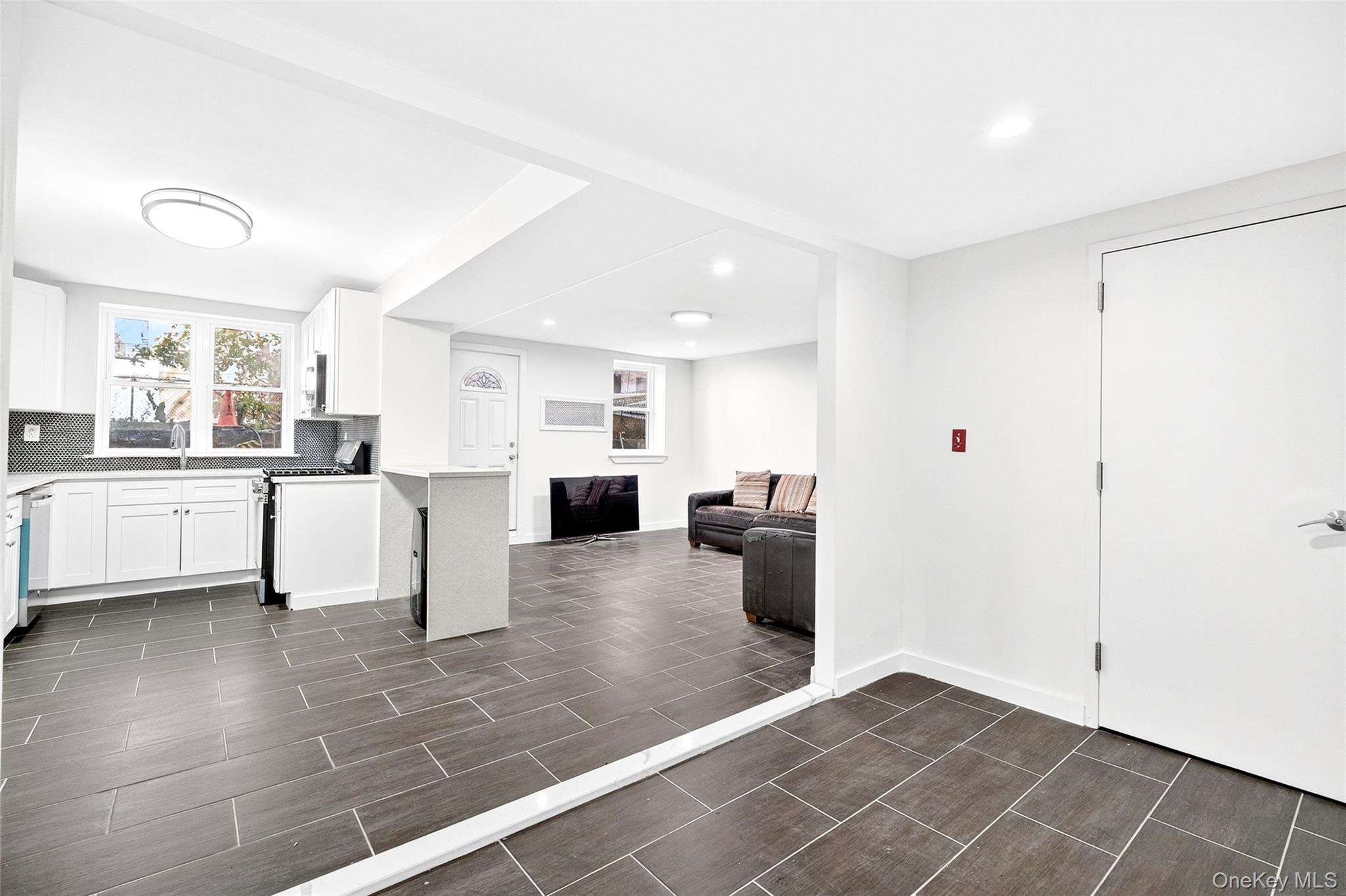 1458 Rowland Street Bronx, NY 10461 - Photo 49 of 49 Kitchen with white cabinetry, open floor plan, stainless steel appliances, backsplash, and wood finish floors