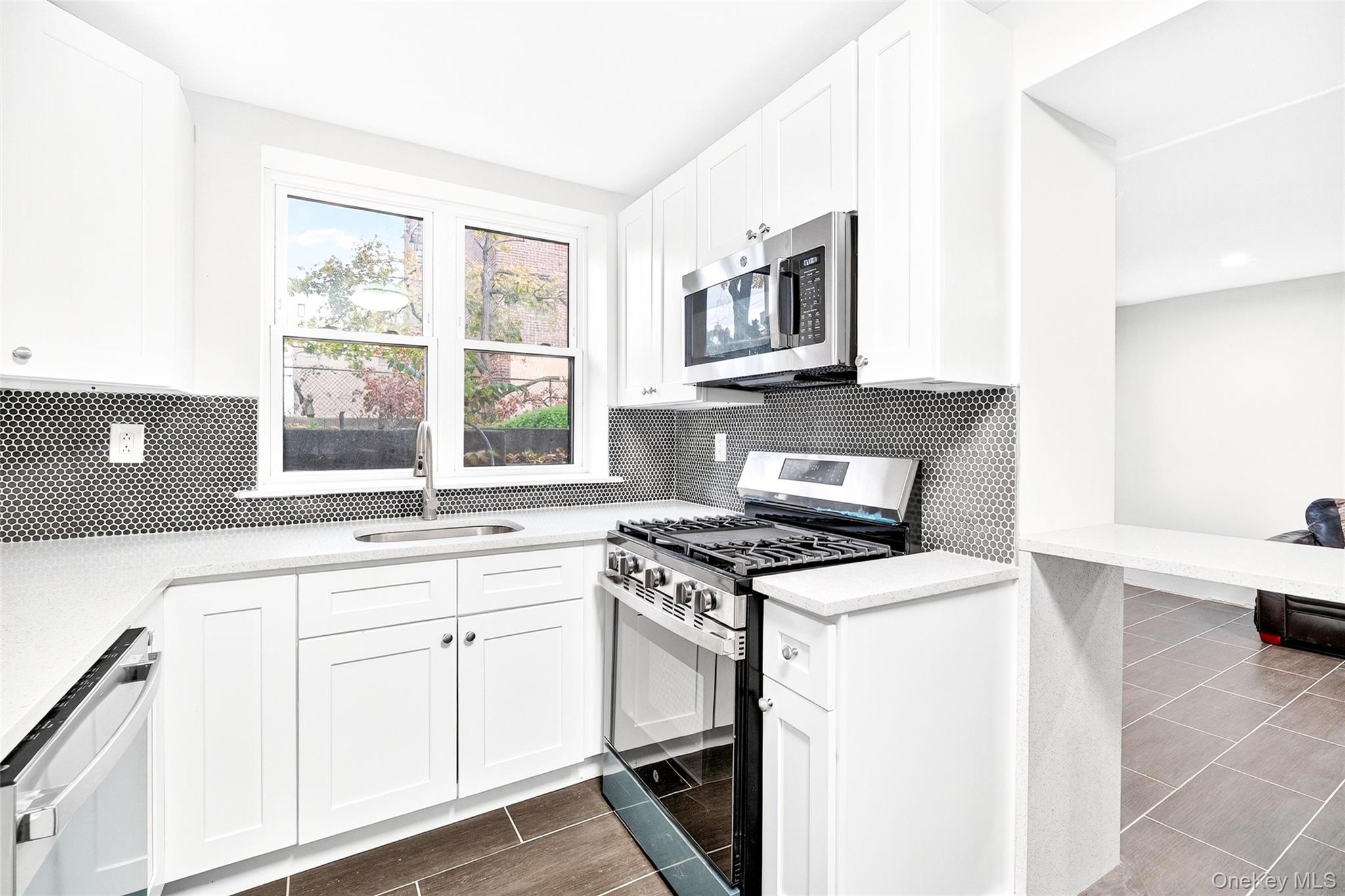 1458 Rowland Street Bronx, NY 10461 - Photo 8 of 49 Kitchen featuring stainless steel appliances, white cabinets, light stone countertops, and tasteful backsplash
