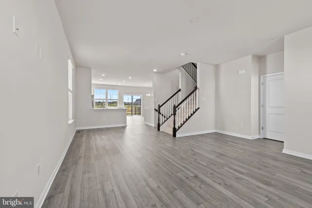 a view of an empty room with wooden floor a ceiling fan