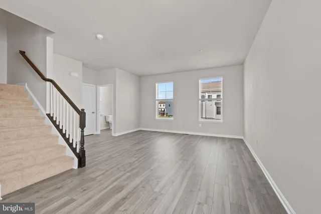 a view of an empty room with wooden floor and stairs