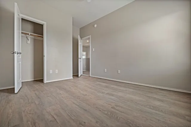 a view of an empty room with wooden floor and closet