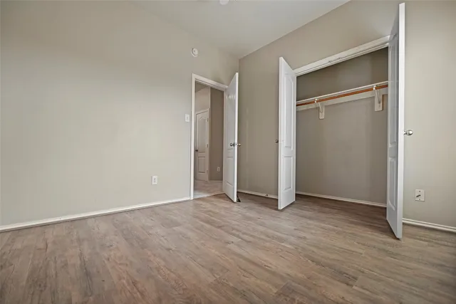 an empty room with wooden floor & closet area