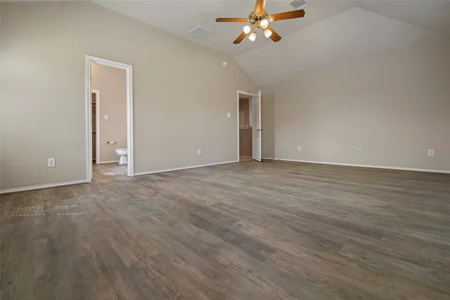 a view of an empty room with chandelier fan and wooden floor