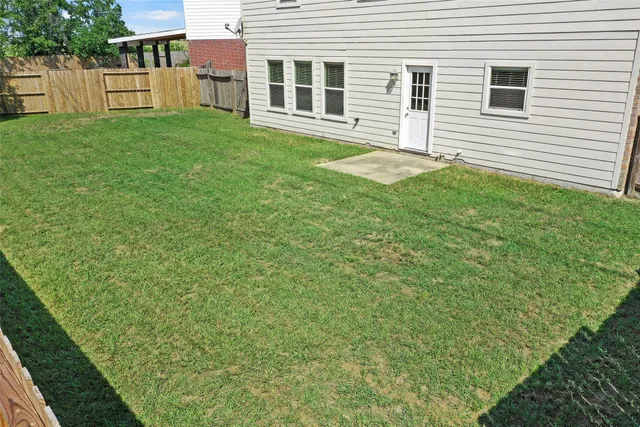 a backyard of a house with large trees and barbeque oven