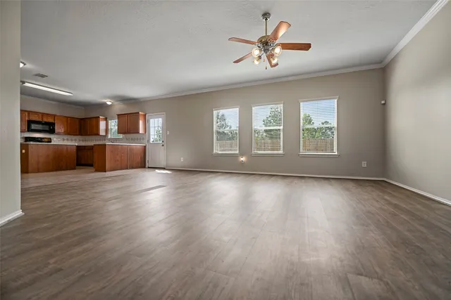 a view of an empty room with a kitchen and wooden floor