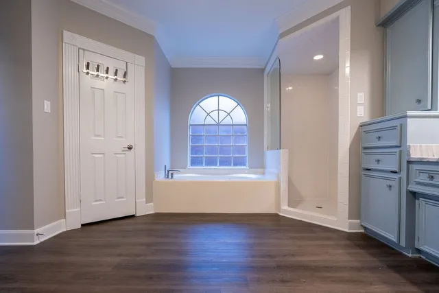 an empty room with wooden floor cabinet and windows