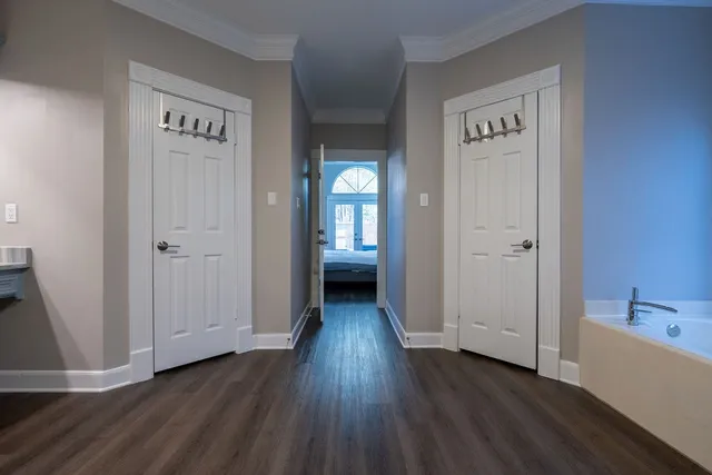a view of a hallway to an empty room with wooden floor and a bathroom