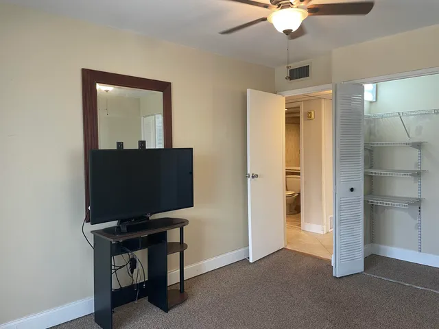 a living room with a flat screen tv and a ceiling fan