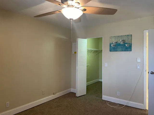 an empty room with closet and a chandelier fan