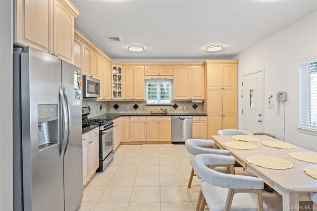 a large kitchen with kitchen island a refrigerator a sink dishwasher a stove a dining table and chairs