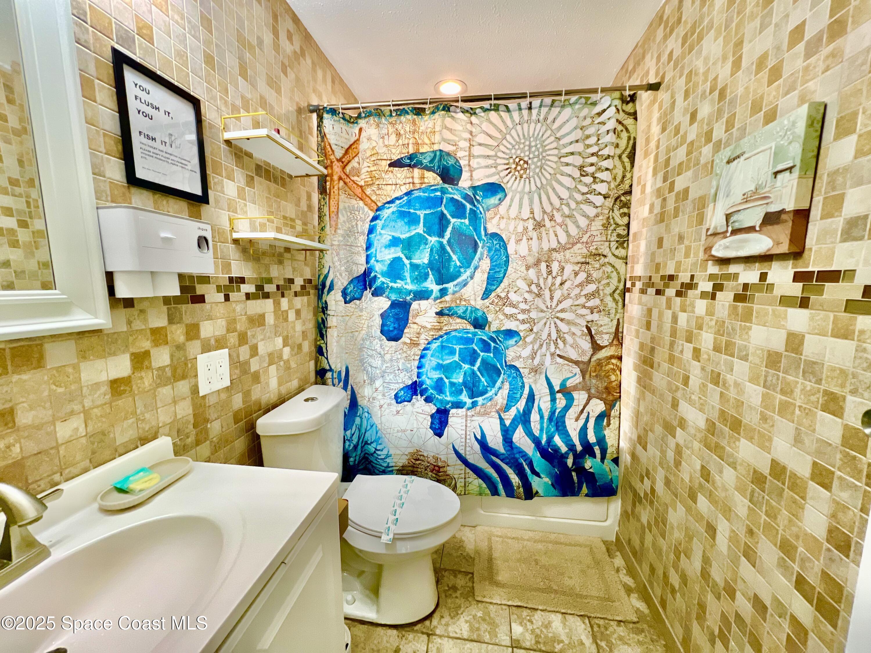 133 Northeast 1st Street Satellite Beach, FL 32937 - Photo 13 of 27 a bathroom with a sink toilet and shower curtain