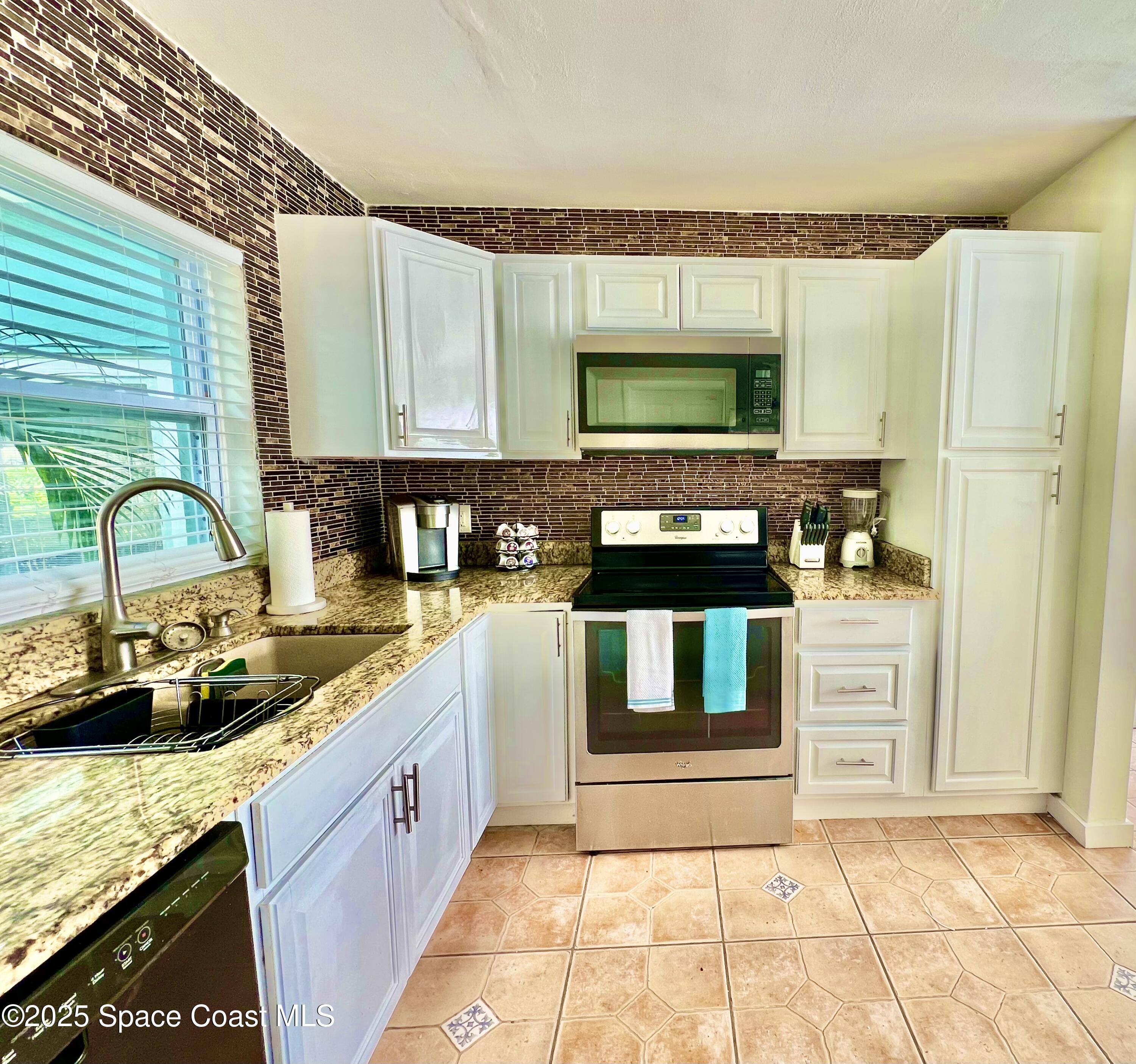 133 Northeast 1st Street Satellite Beach, FL 32937 - Photo 7 of 27 a kitchen with stainless steel appliances granite countertop a sink stove and cabinets