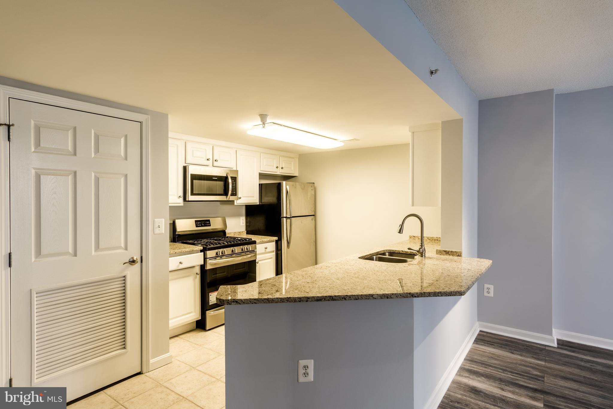 11710 Old Georgetown Road, Unit 422 North Bethesda, MD 20852 - Photo 1 of 29 a kitchen with kitchen island granite countertop a sink stove microwave and refrigerator