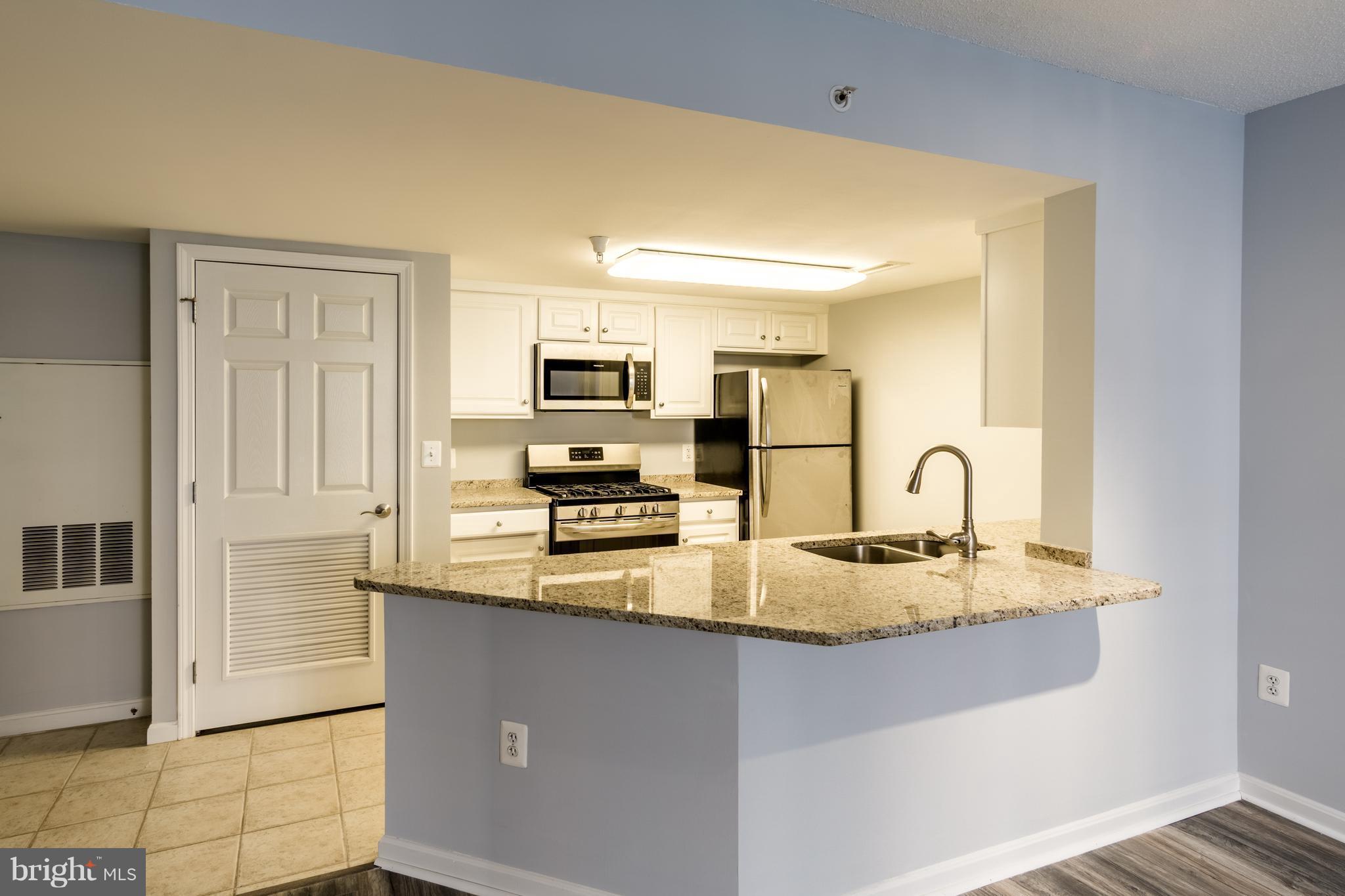 11710 Old Georgetown Road, Unit 422 North Bethesda, MD 20852 - Photo 3 of 29 a kitchen with kitchen island granite countertop a stove top oven a sink a counter space and cabinets