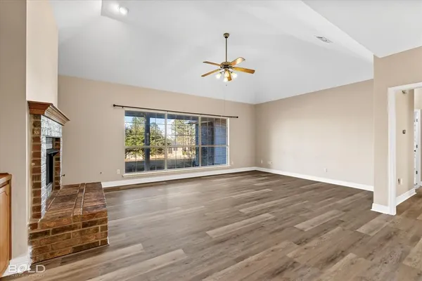 a view of a livingroom with a fireplace a ceiling fan and window