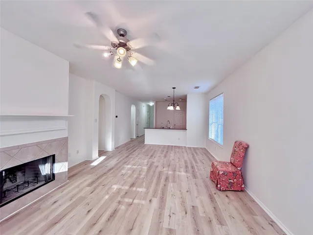 a view of an empty room with chandelier fan and wooden floor