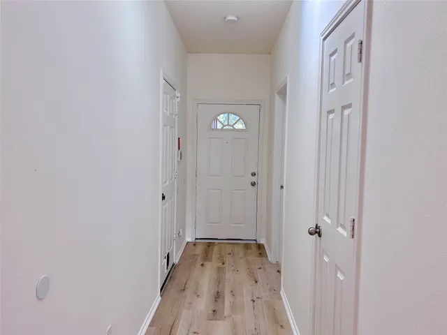 a view of a hallway with wooden floor and a bathroom