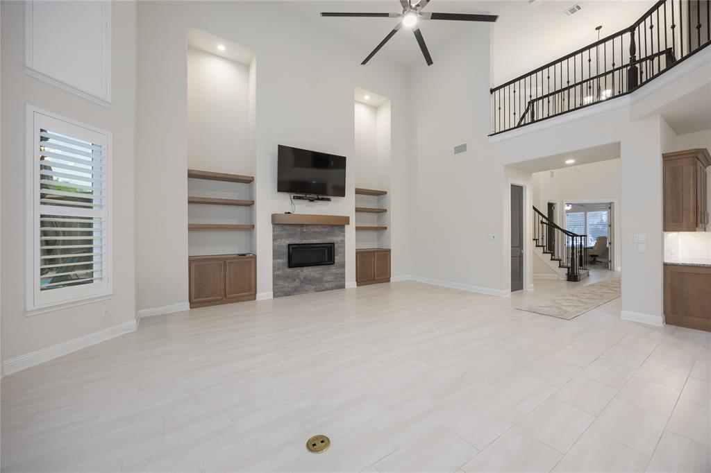 918 Sydney Lane Allen, TX 75013 - Photo 5 of 40 Living area featuring high ceilings, a ceiling fan, light-colored tiled flooring, and a fireplace with a stone surround