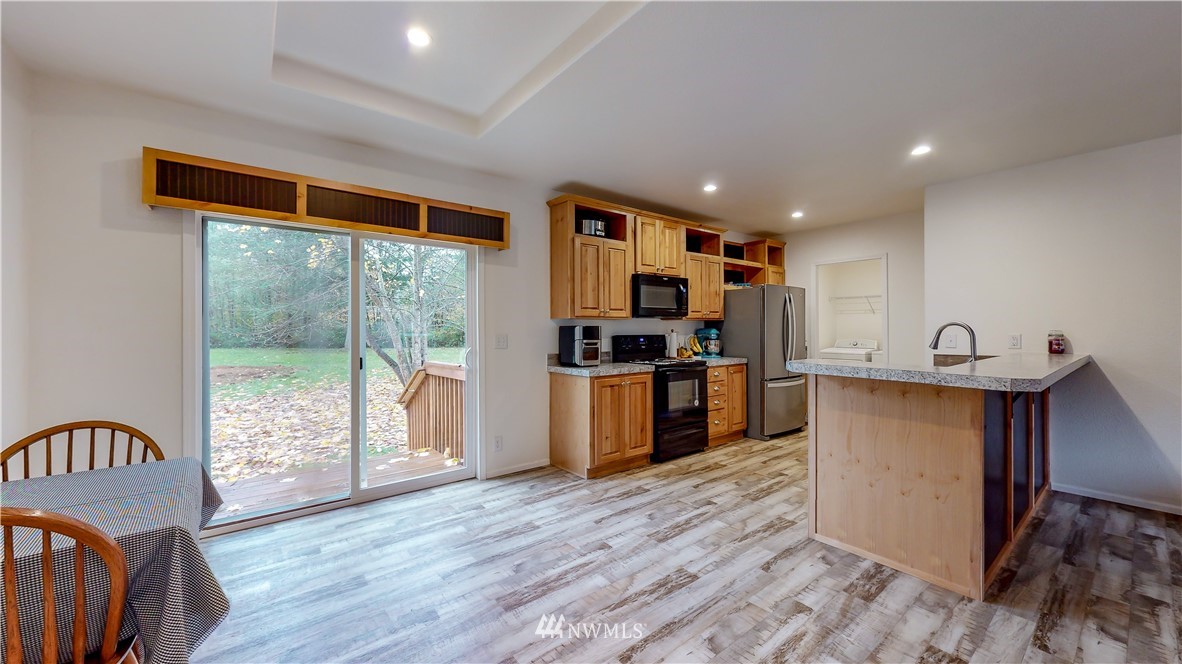 729 Cinebar Road, Unit A Cinebar, WA 98533 - Photo 6 of 30 a kitchen with granite countertop a refrigerator a stove top oven a sink dishwasher and wooden cabinets with wooden floor
