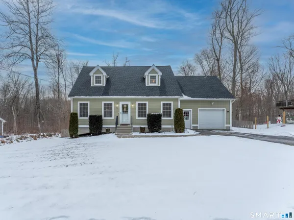 a front view of a house with a yard covered with snow