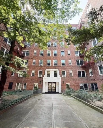 a front view of a building with a yard and parking space