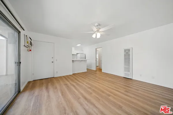 a view of empty room with wooden floor and fan