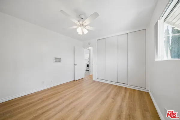 a view of an empty room with wooden floor and window