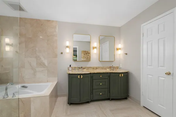 a bathroom with a tub sink mirror and shower