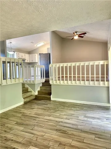 an empty room with wooden floor ceiling fan and windows