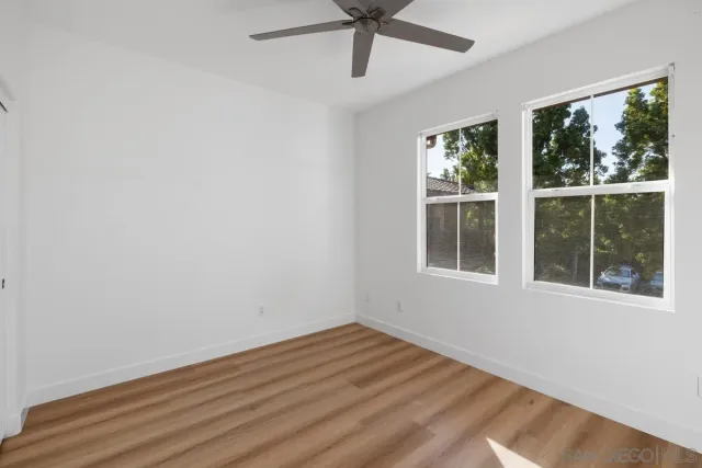 a view of empty room with wooden floor and fan