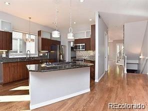 244 South Monroe Street Denver, CO 80209 - Photo 2 of 16 a kitchen with stainless steel appliances kitchen island granite countertop a stove a sink a refrigerator and a oven with wooden floor