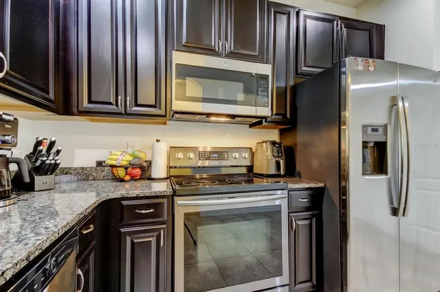 a kitchen with stainless steel appliances granite countertop a refrigerator stove and sink