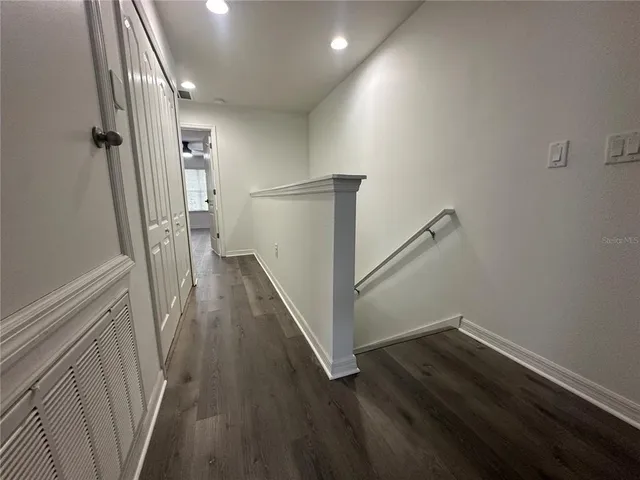 a view of a hallway with wooden floor and staircase