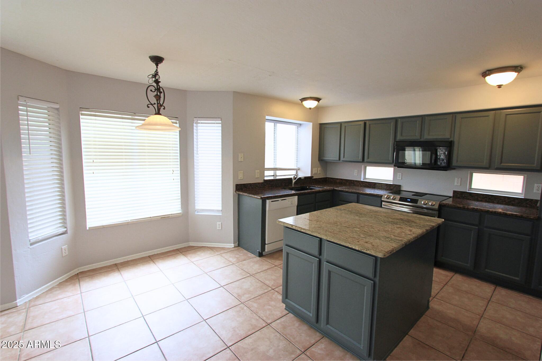 1115 South Tiago Drive Gilbert, AZ 85233 - Photo 5 of 22 a kitchen with stainless steel appliances granite countertop a sink stove and cabinets