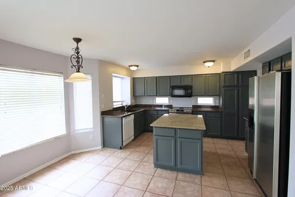a kitchen with kitchen island granite countertop a refrigerator oven a sink and dishwasher