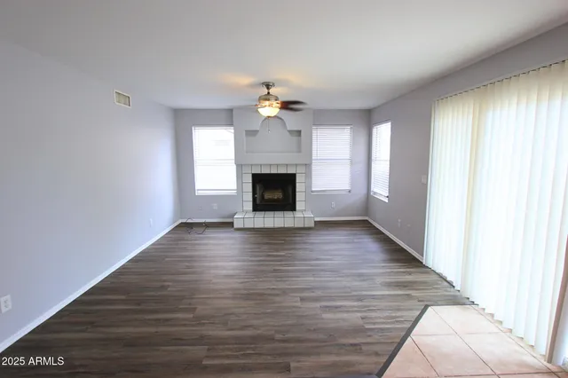 an empty room with wooden floor fireplace and windows