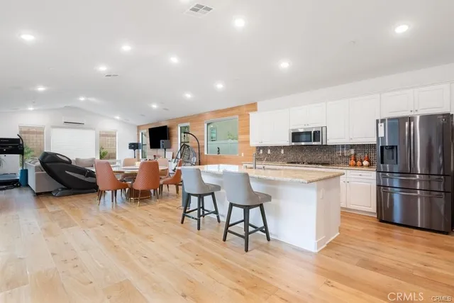 a large white kitchen with lots of furniture and stainless steel appliances