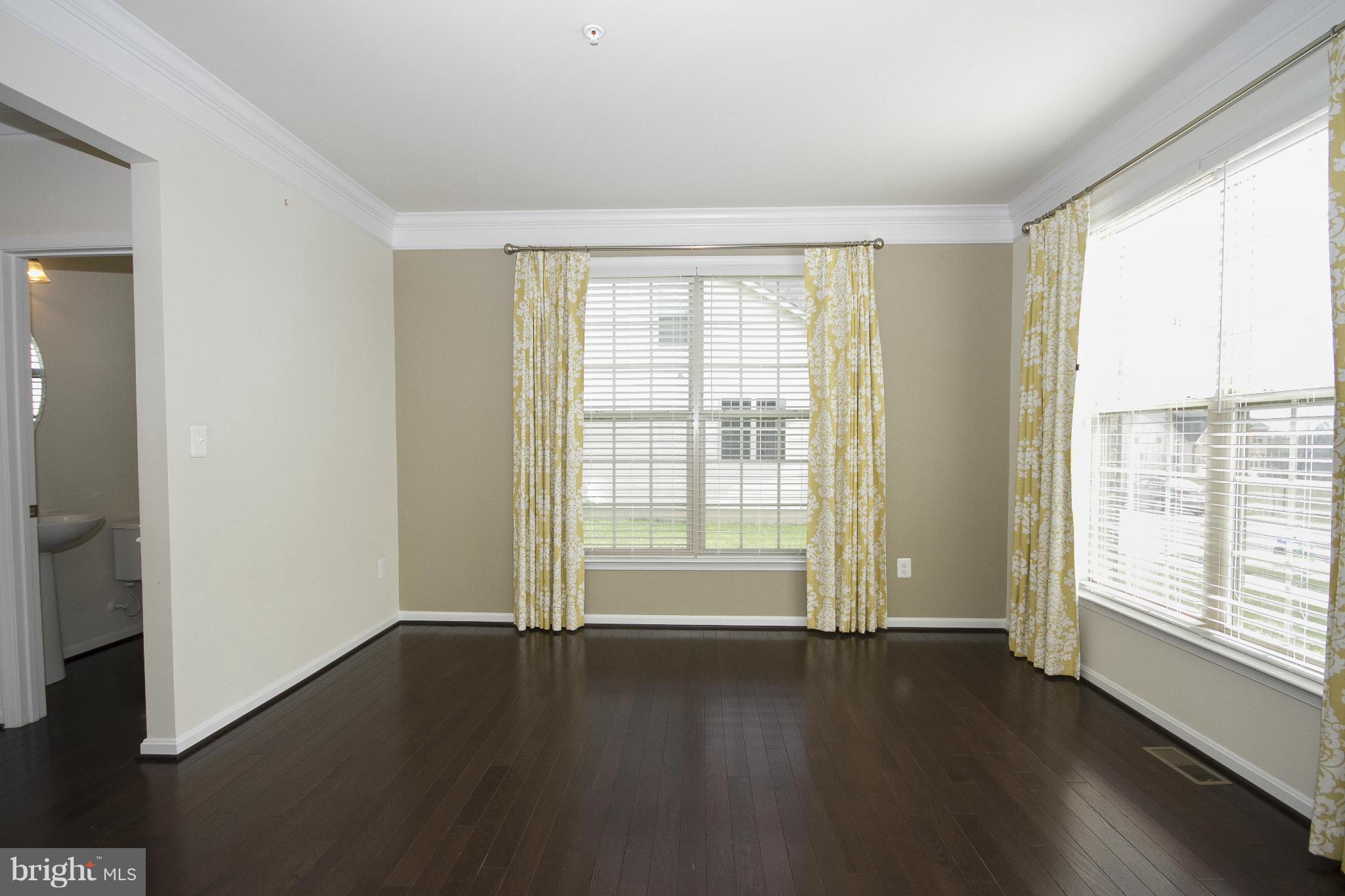 4310 Stoss Road Perry Hall, MD 21128 - Photo 4 of 22 an empty room with wooden floor and windows with curtains view