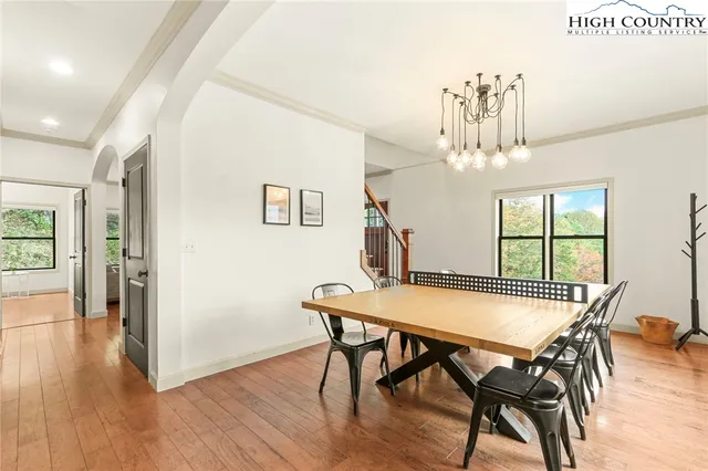 a kitchen with stainless steel appliances granite countertop a refrigerator a sink dishwasher a stove a dining table and chairs with wooden floor