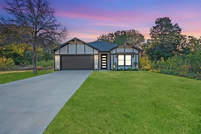 a front view of a house with a big yard and large trees