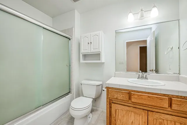 a bathroom with a granite countertop sink toilet and mirror