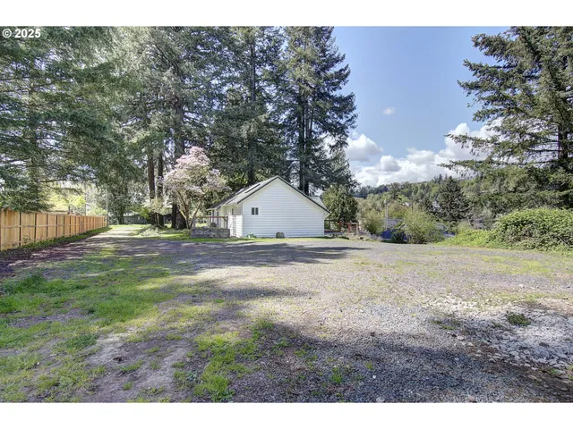 a view of dirt yard with large trees