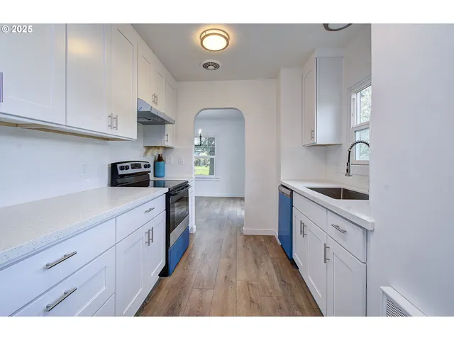 a kitchen with cabinets stainless steel appliances a sink and wooden floor