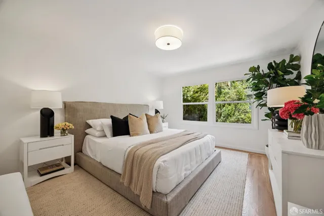 a bedroom with a bed potted plant on dresser and a window
