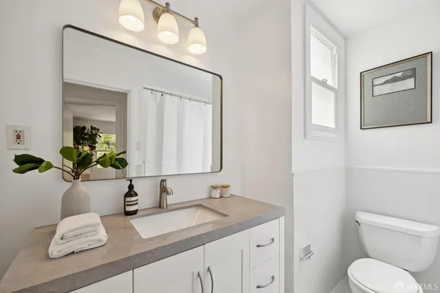 a bathroom with a granite countertop sink mirror and toilet